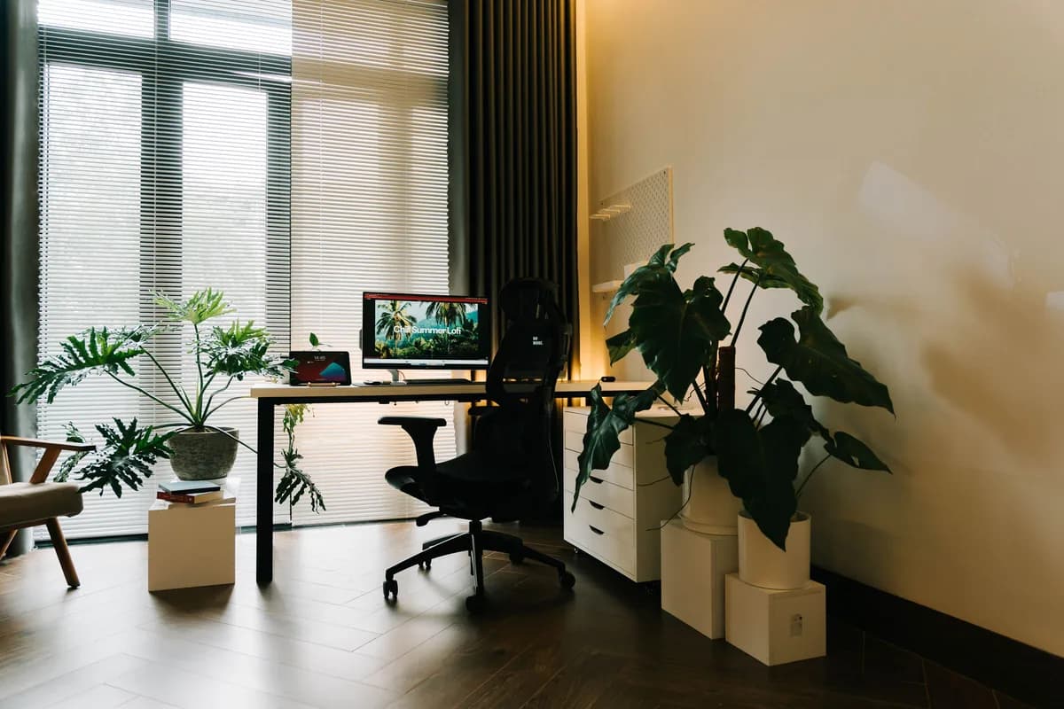 Interior del despacho con ventanal, plantas y una mesa de trabajo despejada
