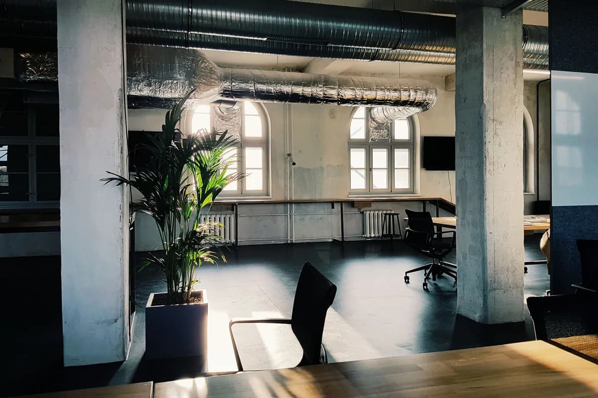 Sala amplia del despacho con ventanales altos, columnas y luz natural